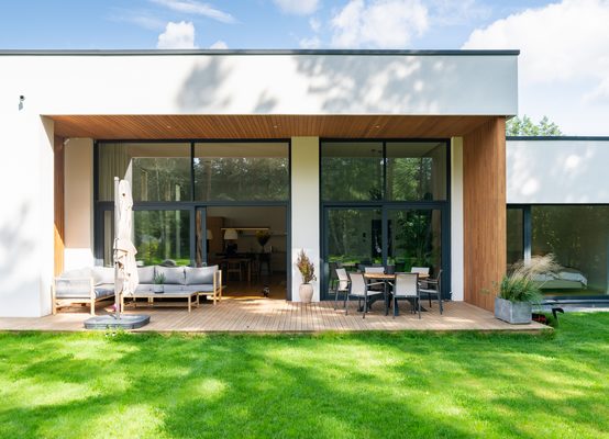 Fachada de casa moderna con amplia terraza y grandes ventanales que dejan entrar abundante luz natural